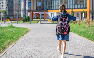 menina chegando à escola com mochila às costas