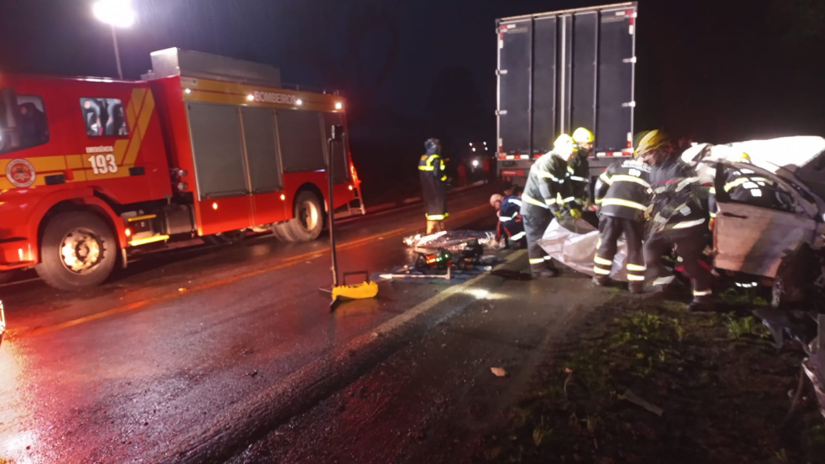 Bombeiros prestando atendimento a vítimas em veículo totalmente destruído, após bater em caminhão na BR282 em Alfredo Wagner.